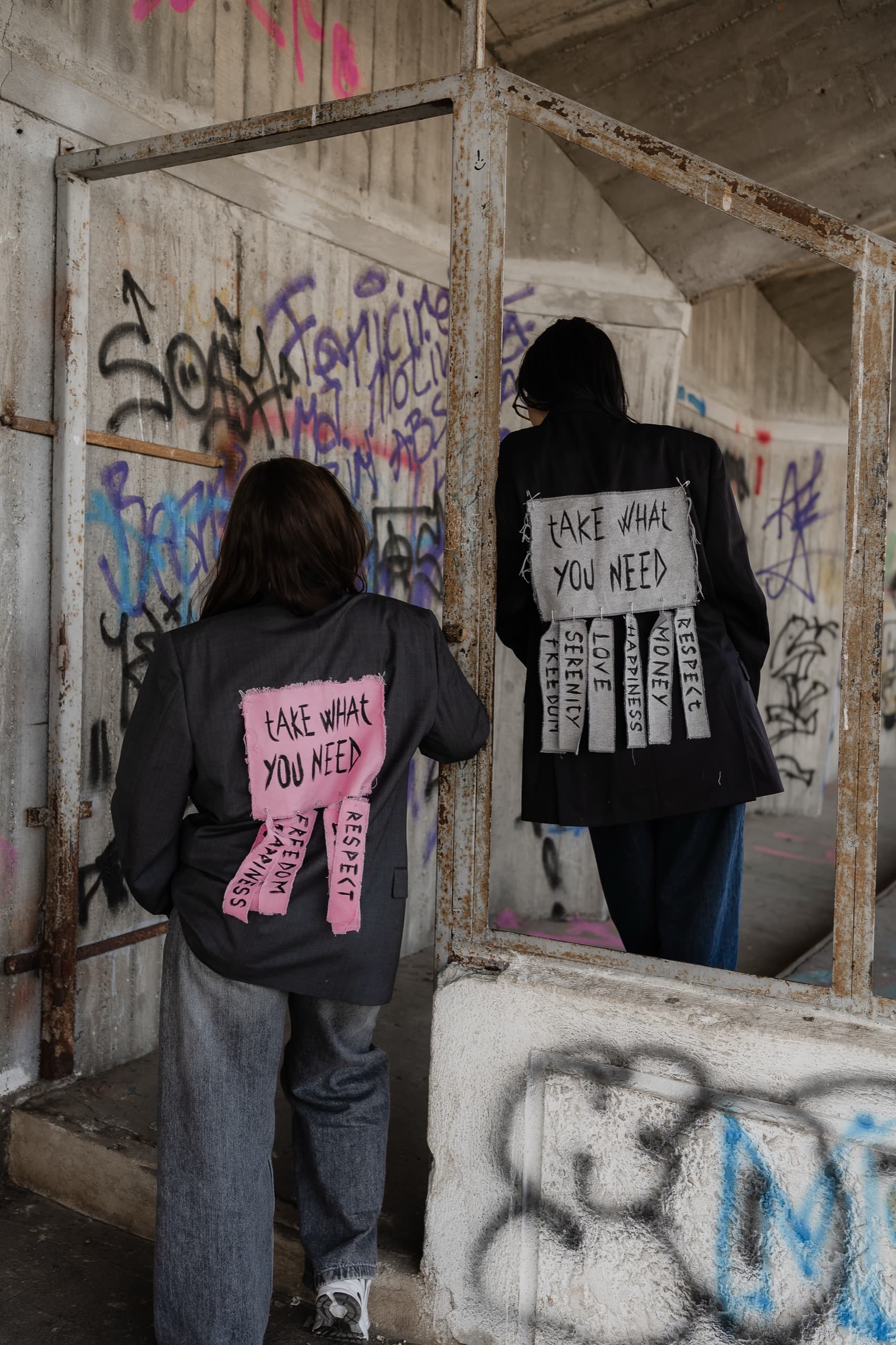 Backs of two reworked blazers with hand-lettered tear-off patches reading take what you need