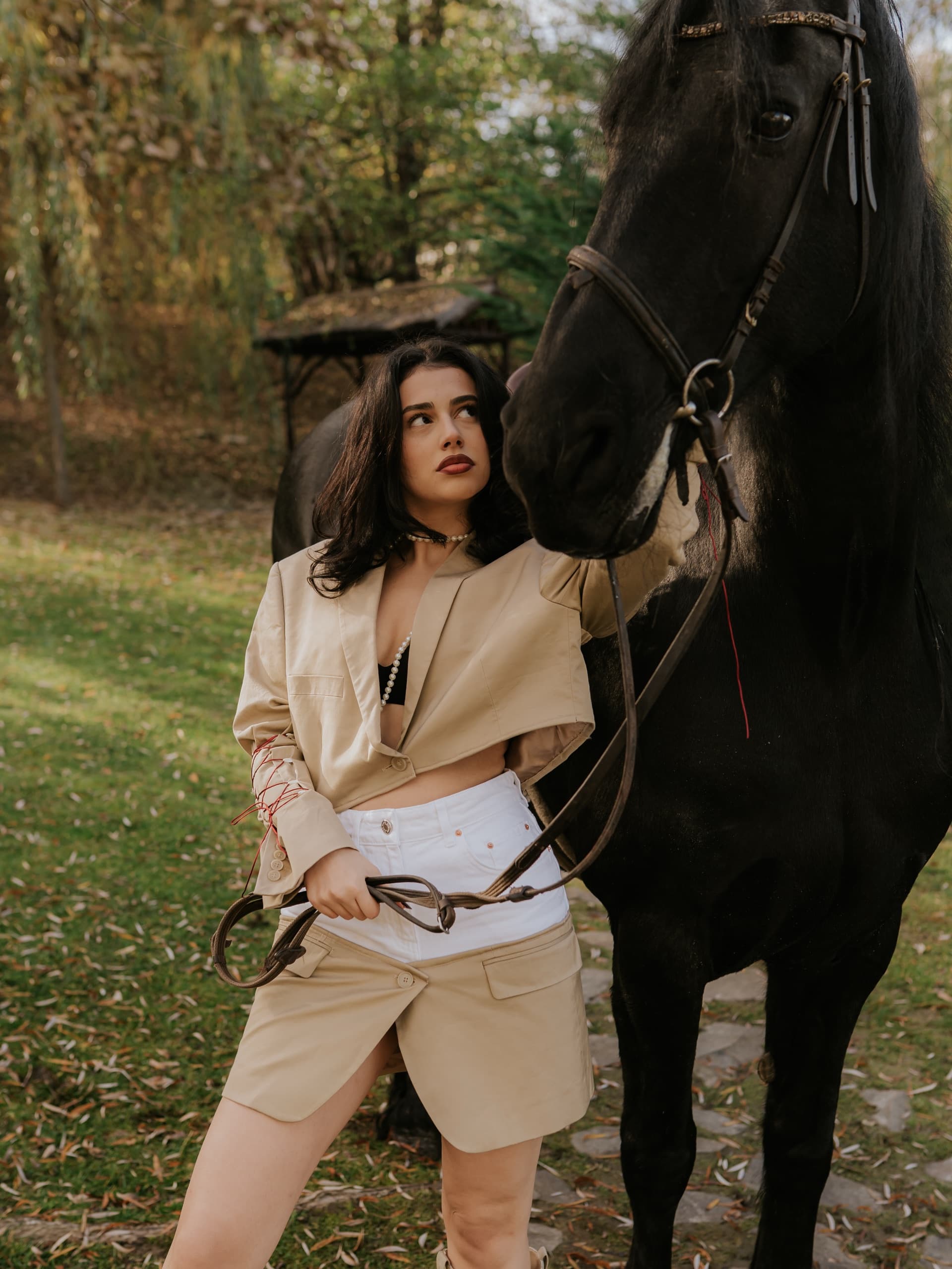 A cropped beige blazer and matching skirt, beside a black horse