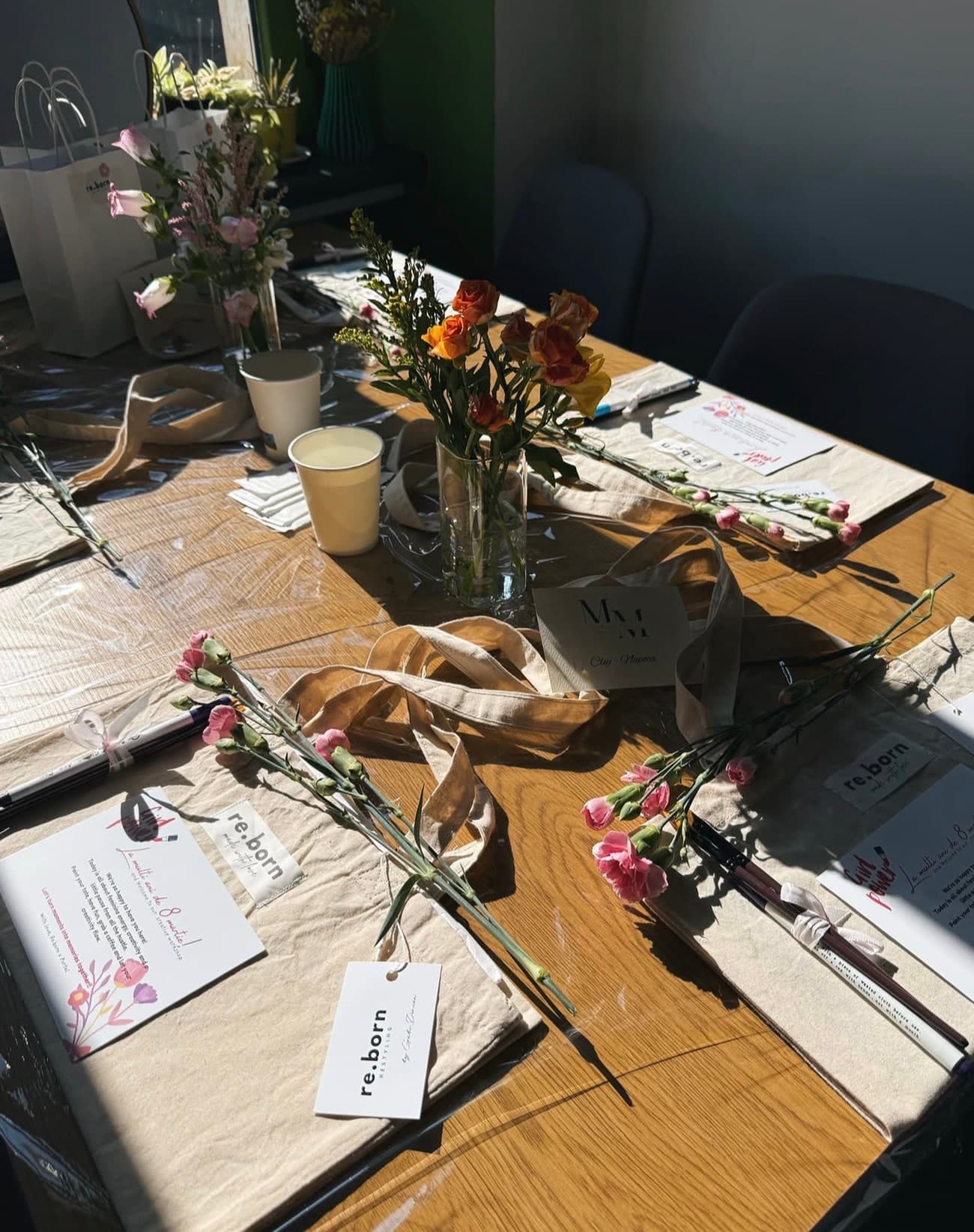 A private event table set with flowers, place cards, ribbons and materials laid out for each guest